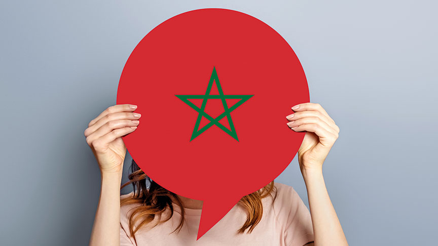 A woman holds up a speech bubble with the flag of Morocco.